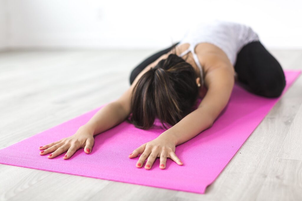 Femme en posture de l’enfant lors d’une séance de Yin Yoga, favorisant la relaxation profonde et l’étirement doux.